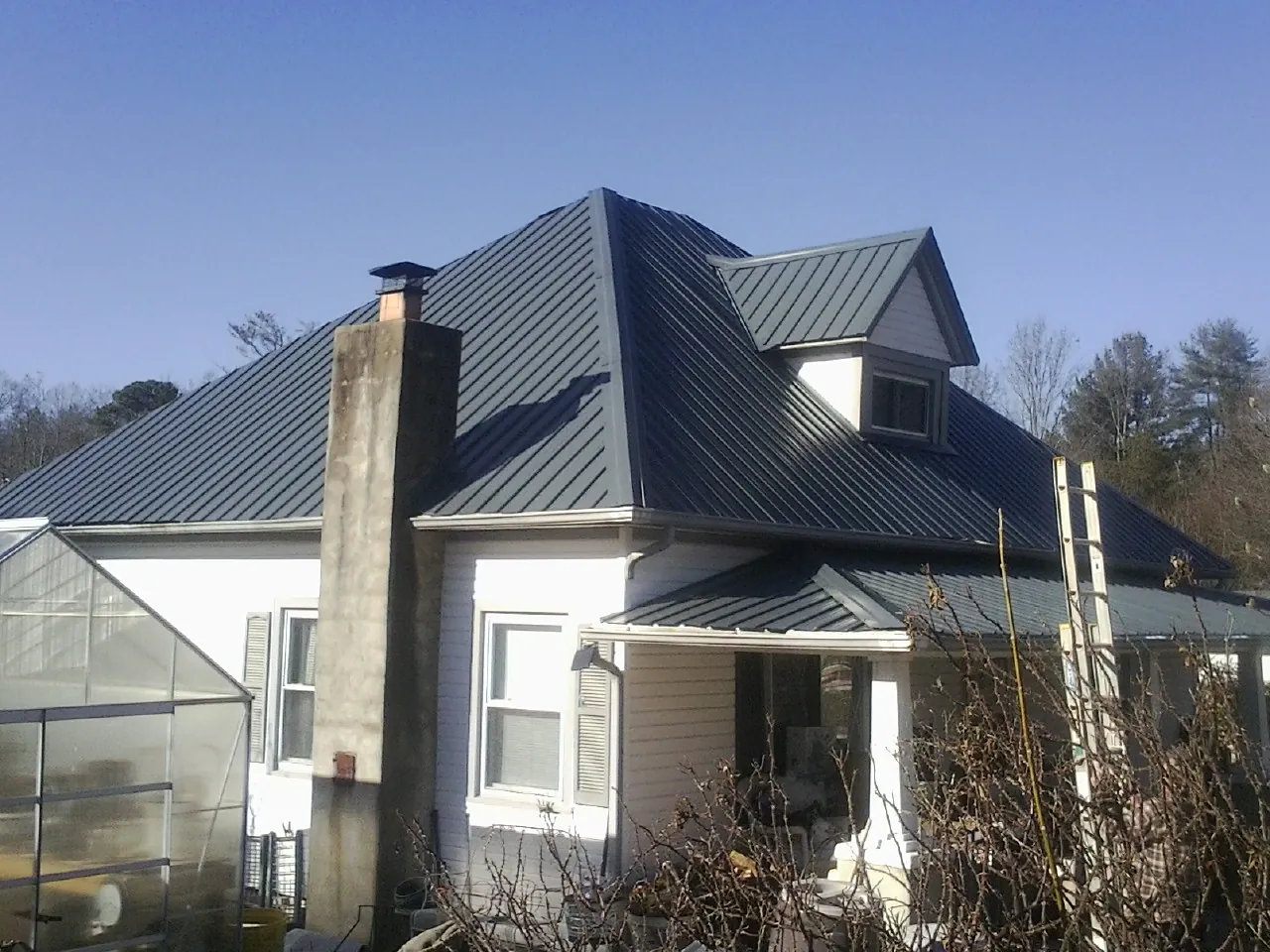 Dark blue standing seam metal roof on a white farmhouse with dormer — Slate & Tile Roof Repair by Roofing Brothers in Hawesville