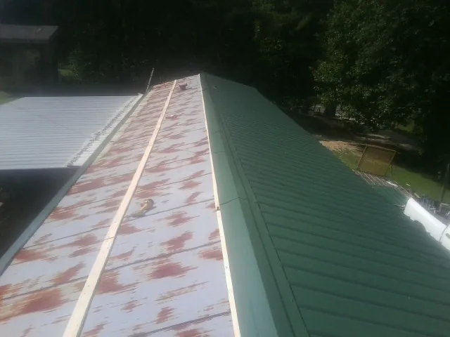 Old rusted panels beside newly installed green metal roofing — Wind Damage Roof Repair by Roofing Brothers in Hawesville