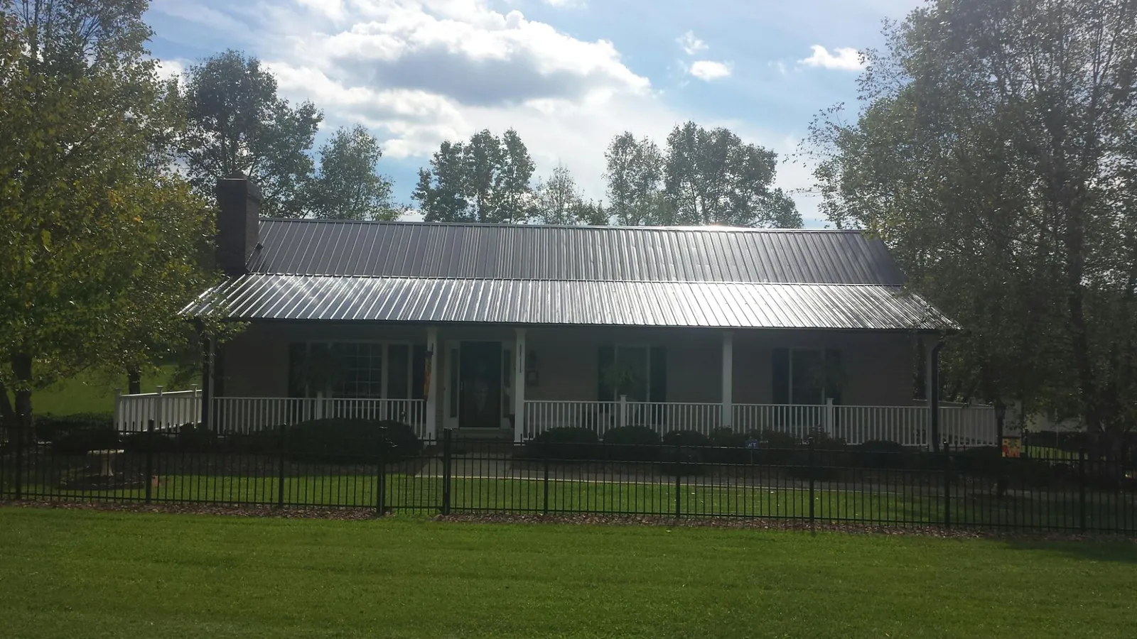 Gray metal roof on a brick ranch with a full width front porch — Gutter Guard Installation work by our crew in Hawesville