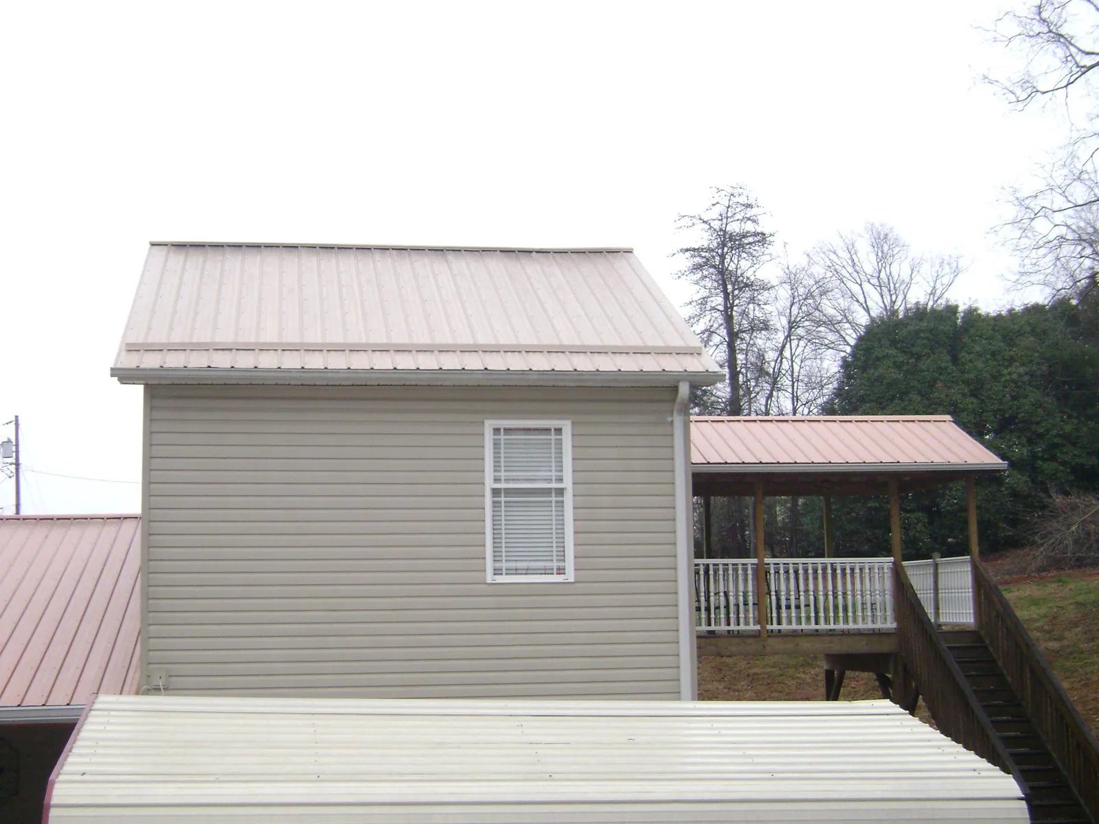 Tan metal roofs on a two story addition and attached porch, from a Roof Replacement job in Hawesville