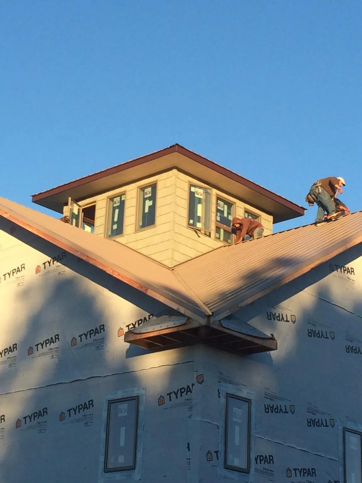 Roofers working around a rooftop cupola on a new metal roof at sunset — Roof Waterproofing in Hawesville by Roofing Brothers